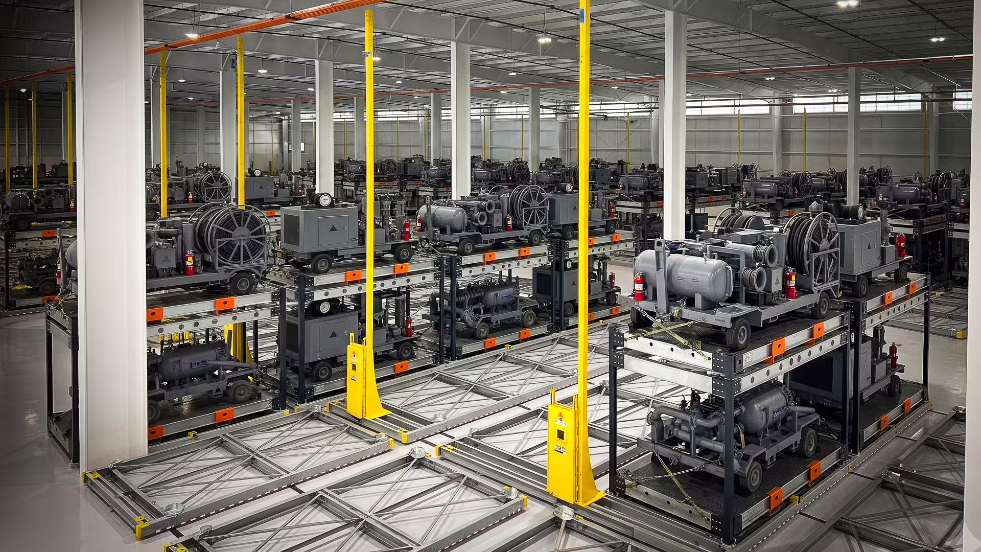 An elevated view across a RollingStack installation, several parallel runs of crates loaded with plant and equipment, yellow guide posts marking the run ends