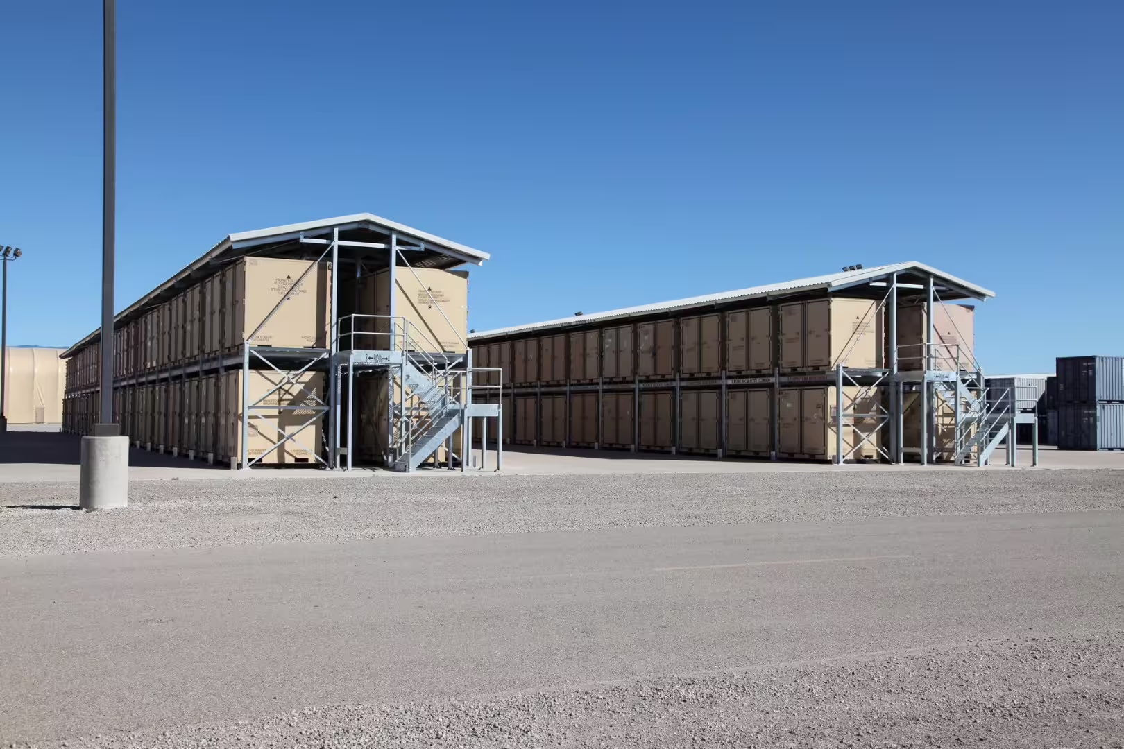 Two-tier CargoRack container racking with steel access stairs at a desert storage yard