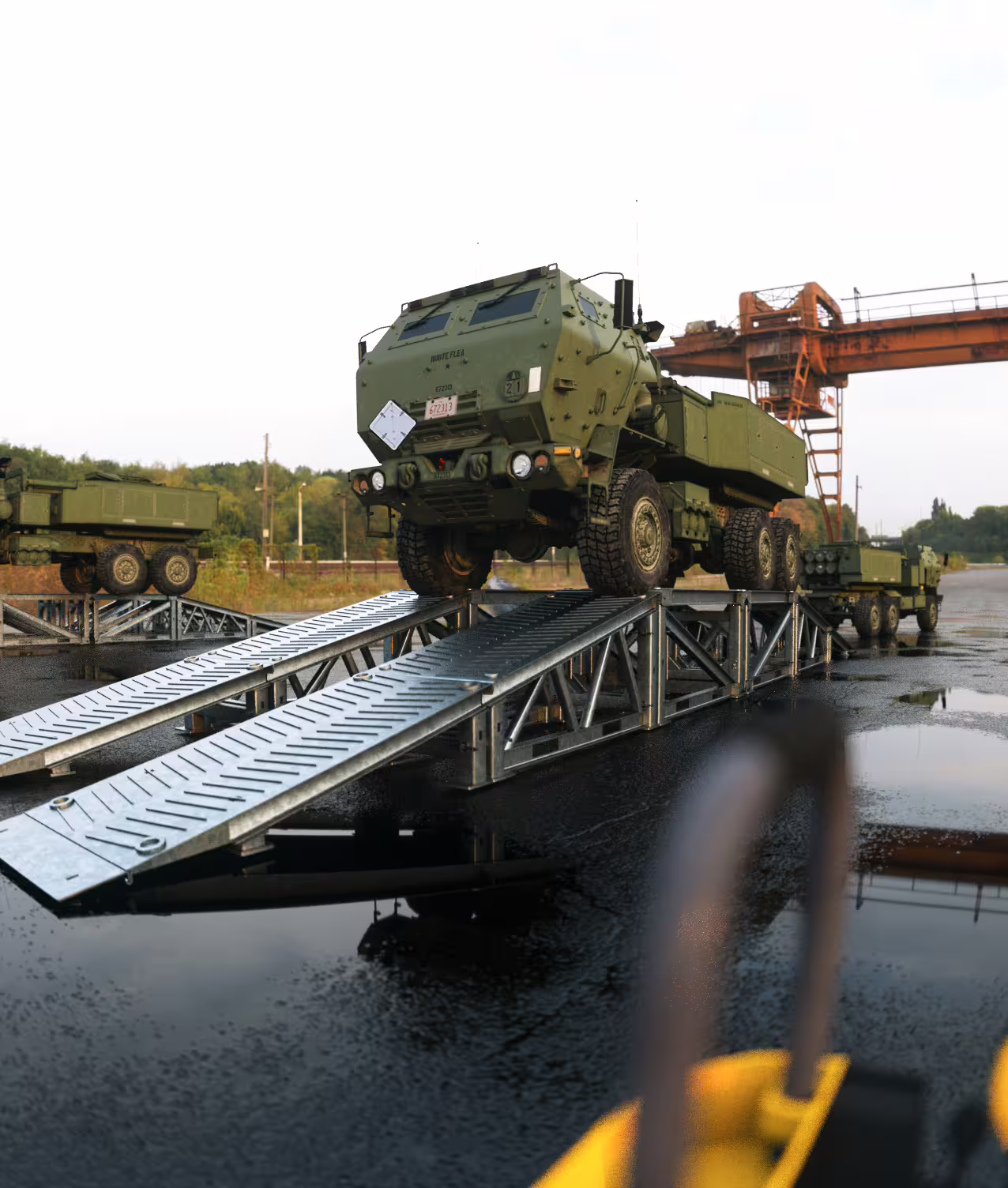 HIMARS launcher parked on a drive-through MUDR-PD/WR wash ramp on wet hardstanding
