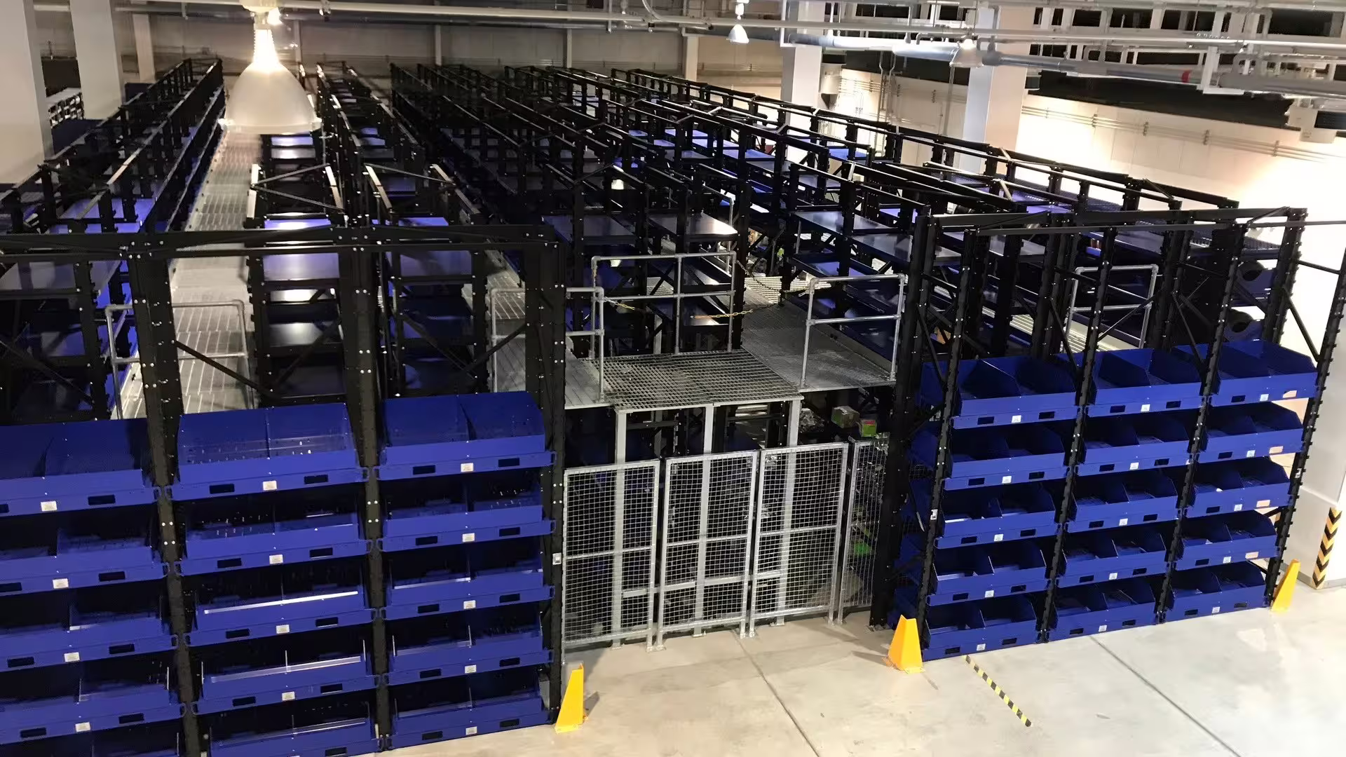 RackMezz installation — blue bin-front racking blocks around a caged steel mezzanine platform