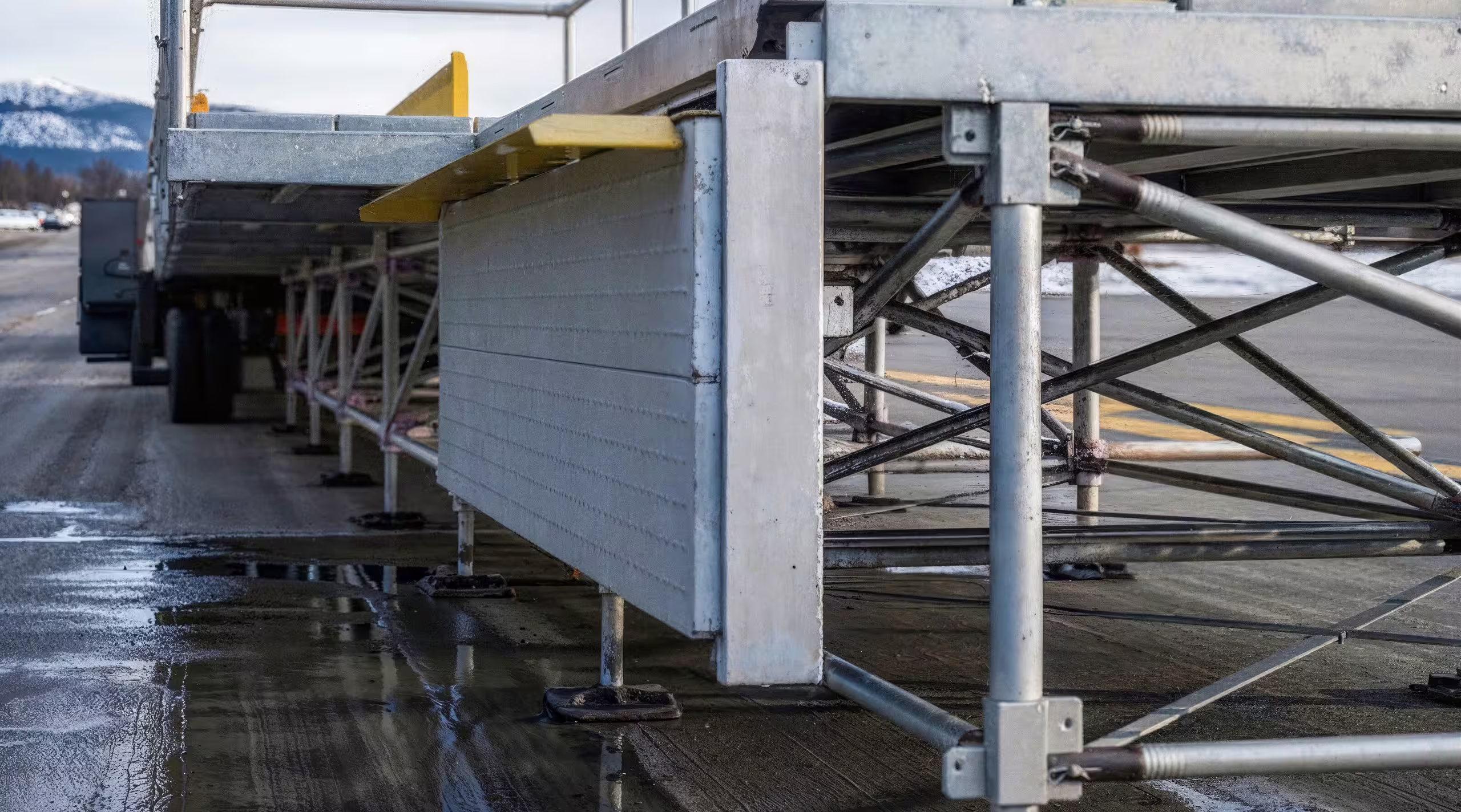An Air Cargo Dock seen from ground level along its length, height-adjustable legs on base plates and truss bracing under the deck