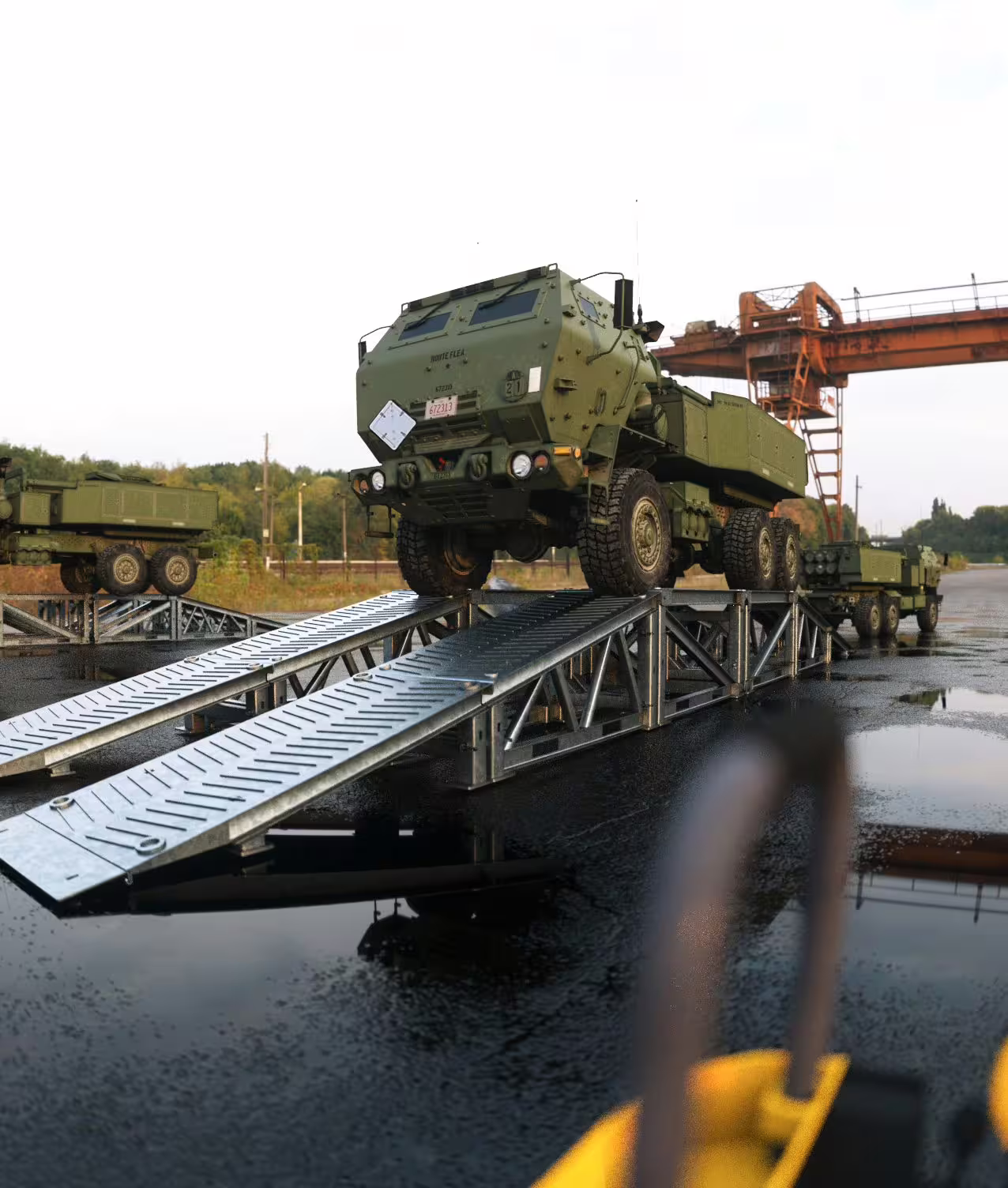 HIMARS launcher crossing a drive-through MUDR-PD50 ramp on wet hardstanding