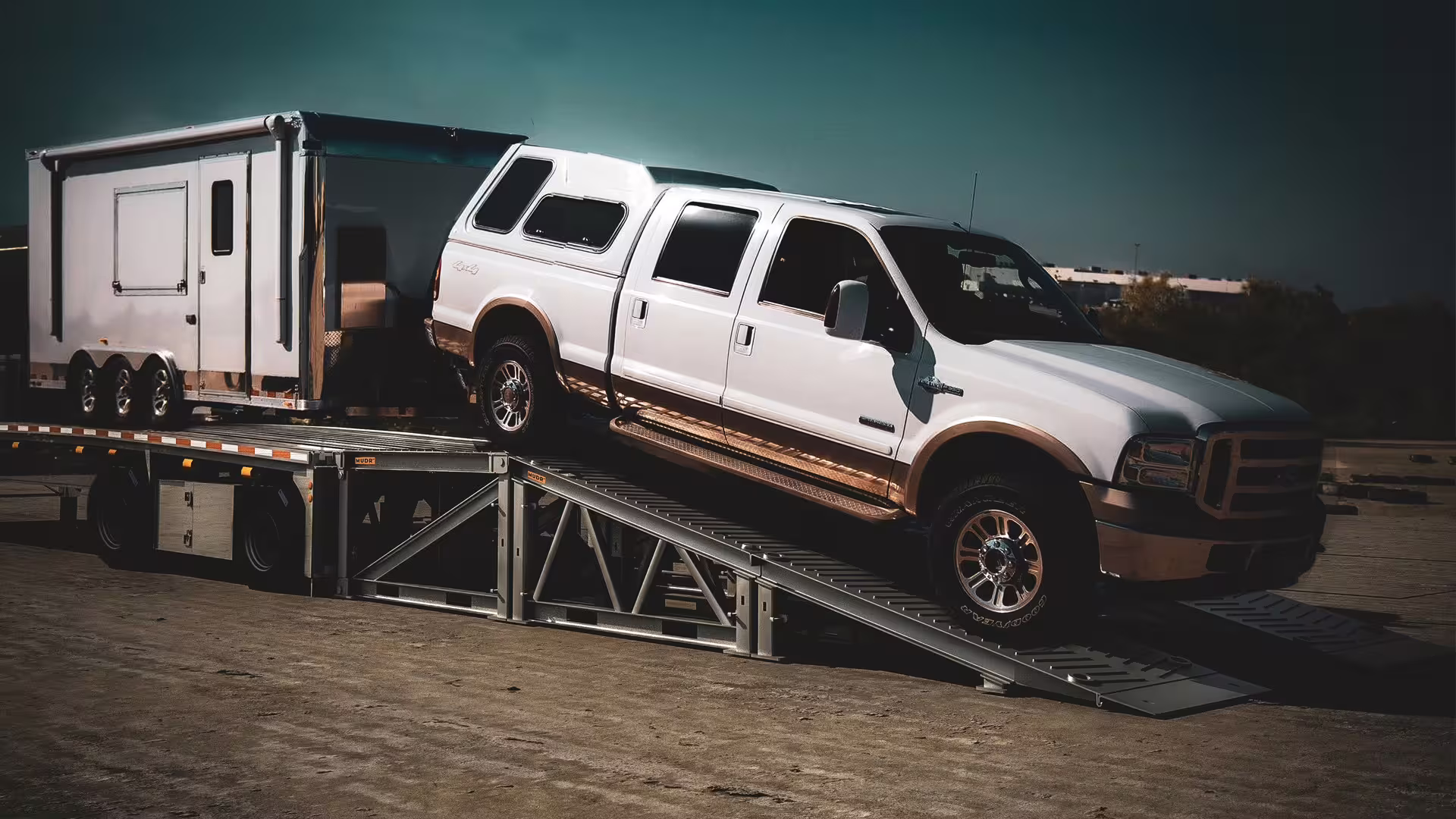 Pickup truck driving down a MUDR-PD50 ramp from a transporter trailer