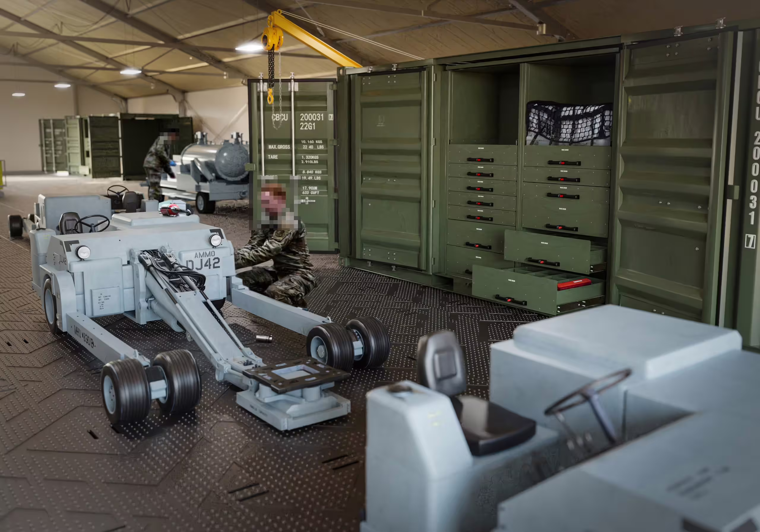A Rackbox container standing open inside a fabric maintenance shelter with drawer stacks and a netted bay exposed, personnel working alongside and wheeled ground-support equipment on a matted floor