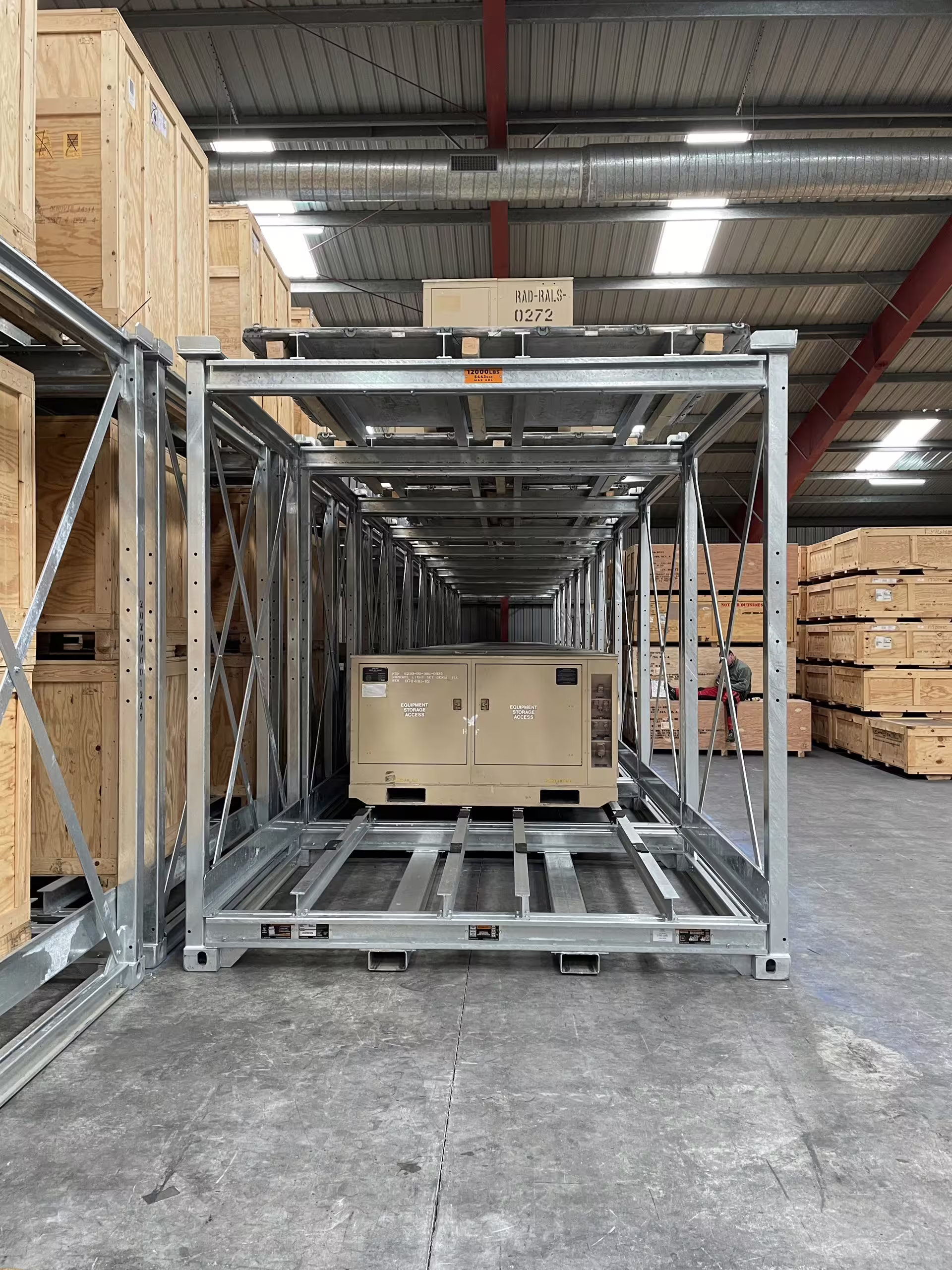 Looking through an empty CargoCuber frame down a warehouse row, the adjustable mid-shelf and corner uprights in view and further loaded frames beyond